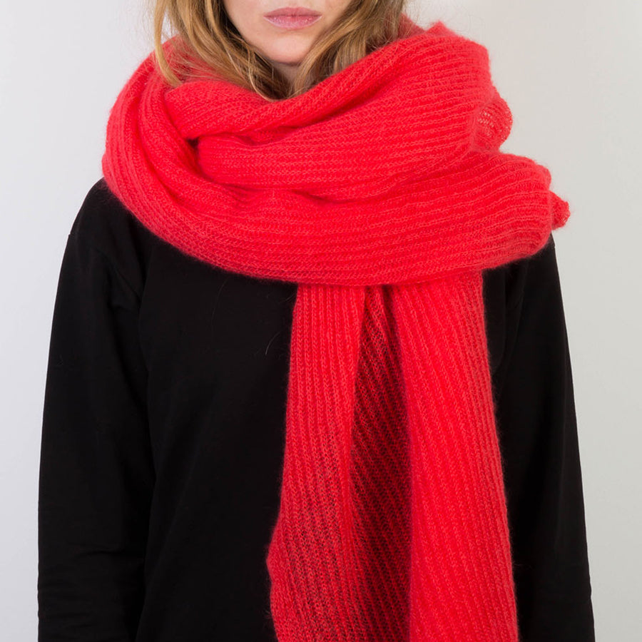 Person trägt orange-pinken, großen gestrickten Mohairschal.