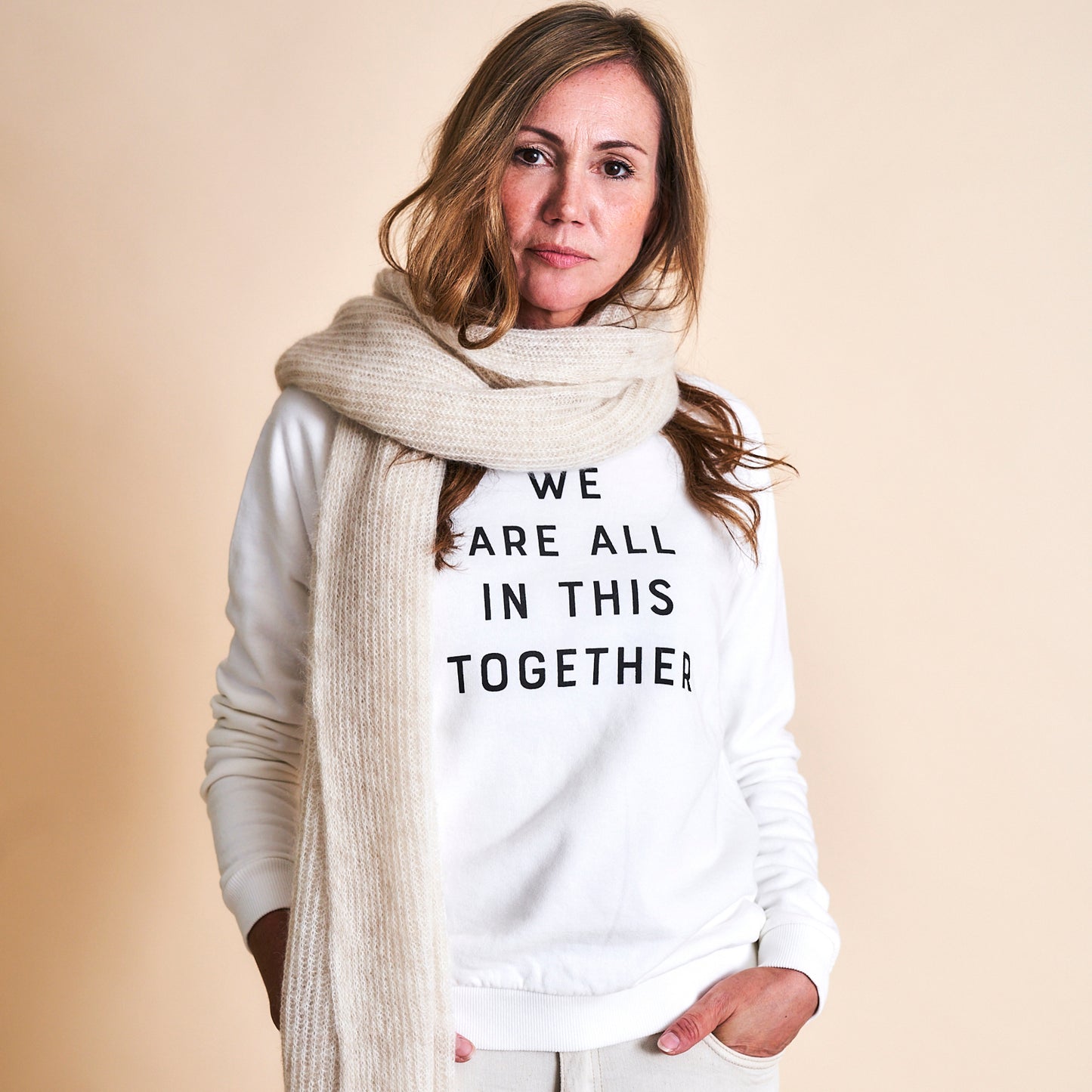 Frau trägt cremefarbenen Mohair Schal und mmies Logo Swaeter