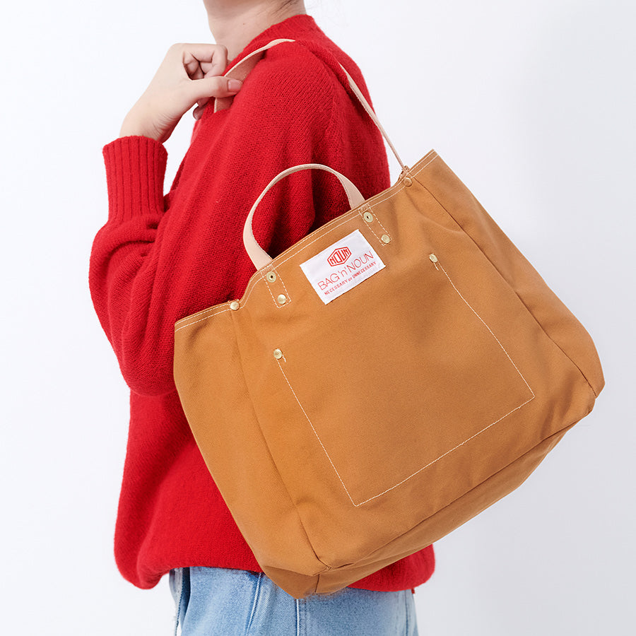 Peson mit brauner Tasche von BAG'n'NOUN,  das Modell heißt Duck Toolbag Short, die Farbe heißt Gold 